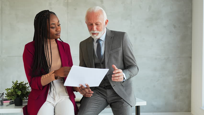 Multiethnic team working together talking developing business strategy in modern office. African American businesswoman manager and senior businessman coworker sharing ideas at workplace. | Shutterstock HD Video #1099724071