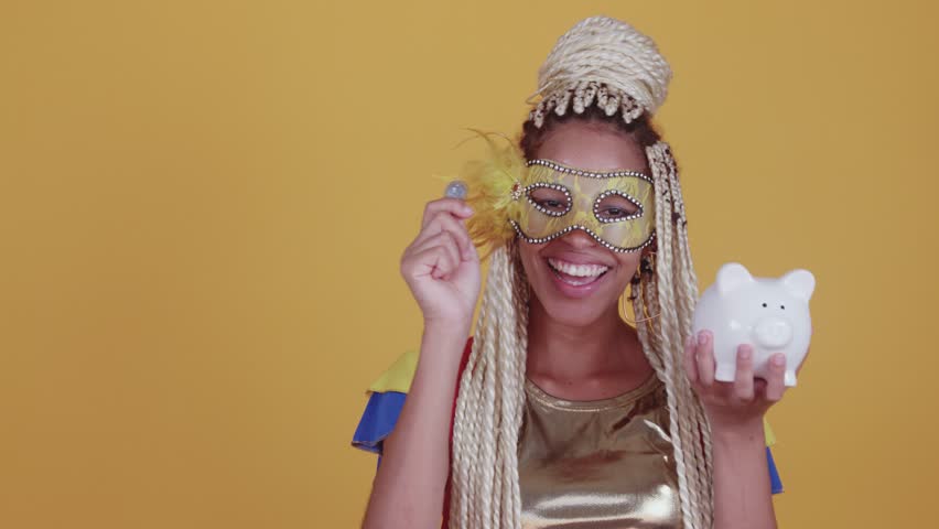 beautiful black, brazilian woman with braids, wearing clothes for carnival. Holding coin and piggy bank.