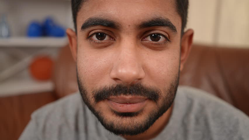 Close-up face of bearded young Middle Eastern man with mustache black hair and brown eyes looking at camera. Smiling confident handsome guy posing indoors | Shutterstock HD Video #1099726595