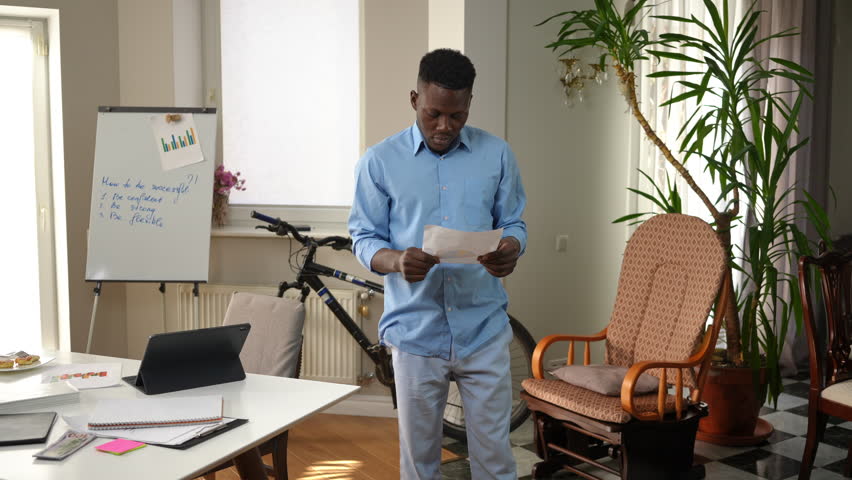 Frustrated tired young man tearing paperwork standing in home office sighing shaking head. Portrait of overworking African American freelancer planning new business idea losing inspiration | Shutterstock HD Video #1099726651