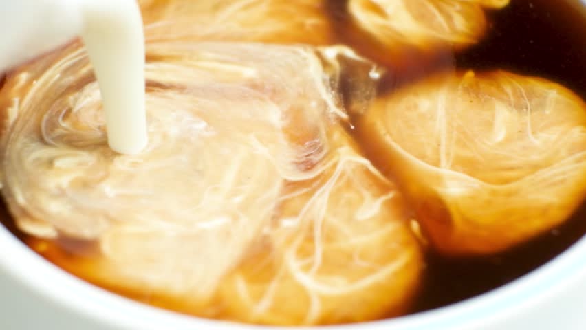 Cream is poured into coffee, making coffee with cream, cappuccino. Dissolving milk cream in coffee, macro. | Shutterstock HD Video #1099726695