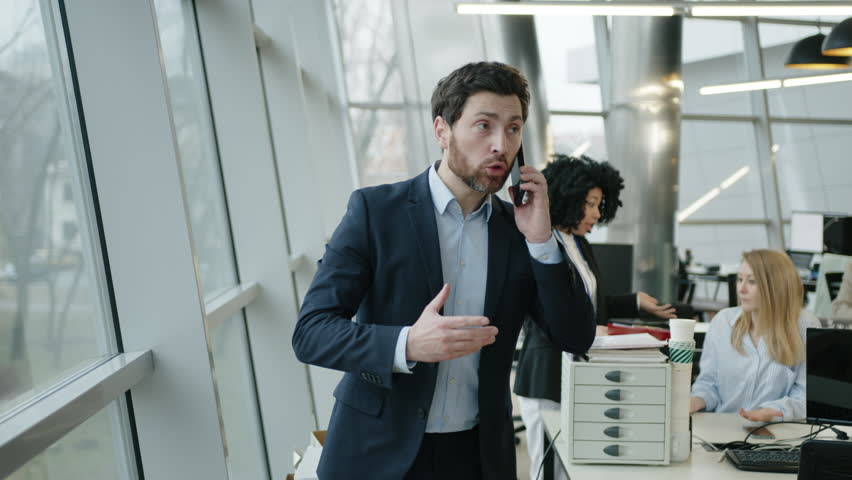 Close-up view of emotional CEO of the company looking disappointed and emotional. Portrait of caucasian businessman in his 40s arguing on the phone. High quality 4k footage | Shutterstock HD Video #1099729003
