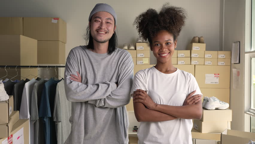 Confident mixed race young couple of Asian man and African-American woman retail seller, entrepreneur, online store drop shipping small business owner looking at camera in delivery shipping warehouse Royalty-Free Stock Footage #1099729321