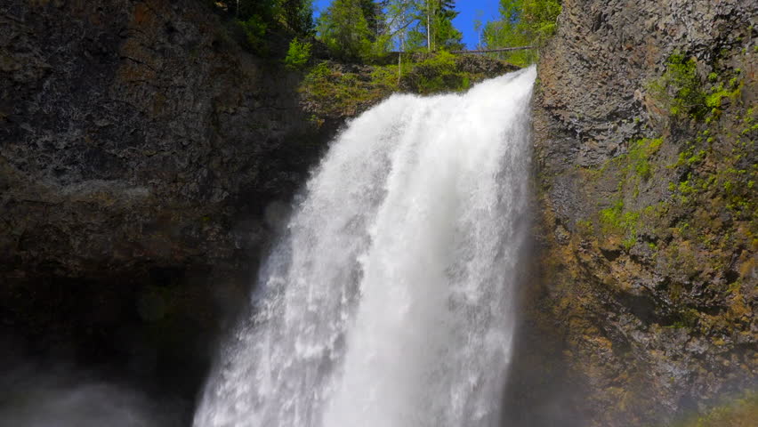 Establishing shot of majestic mountain waterfall with mountain background in Vancouver, Canada, North America. Day time on July 2022. Still camera view. ProRes 422 HQ.
