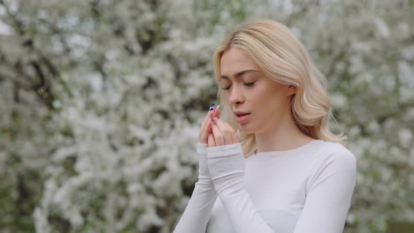 Frustrated young woman scratching watery eyes while standing in spring park. Upset female blonde having health problems due to seasonal allergy outdoors. | Shutterstock HD Video #1099731989