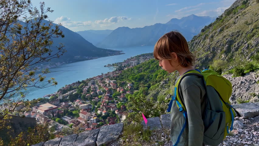 Little boy is walking down from the top of the castle over the city of Kotor in Montenegro. An ancient rocky road leads to the top of the mountain. Slowmotion video