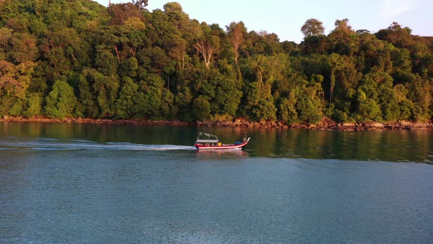 Aerial tracking shot capturing a traditional gondola fishing boat, sailing out to the ocean to catch fish at beautiful sunset golden hour, Langkawi island, Malaysia, Southeast Asia. Royalty-Free Stock Footage #1099734831