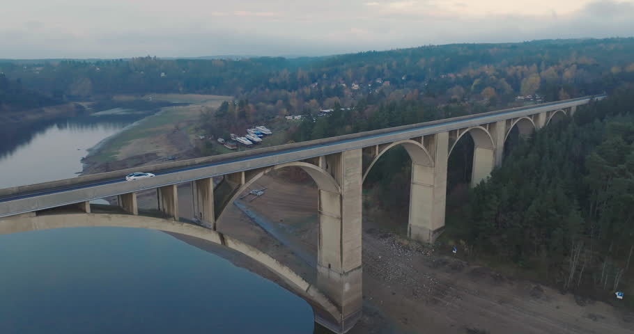 Aerial View of White Car Moving on Bridge Above River on Dark Autumn Day, Drone Shot | Shutterstock HD Video #1099734969