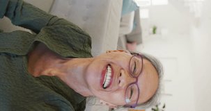 Vertical video of portrait of happy asian senior woman having video call. Active retirement and lifestyle concept.