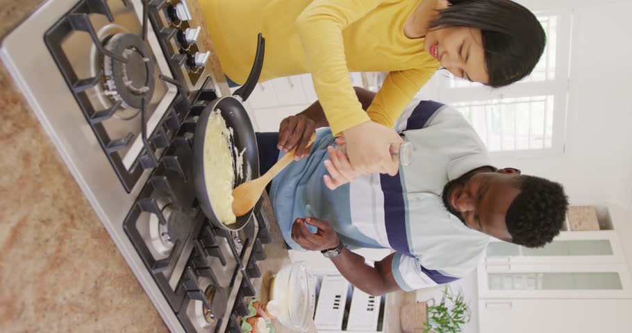 Vertical video of happy diverse couple preparing breakfast in kitchen. Spending quality time at home concept. | Shutterstock HD Video #1099738967