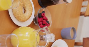 Vertical video of fresh bread and fruit on breakfast with coffee and orange juice on table. Food and lifestyle concept.