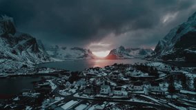 Drone Flight over Reine, Norway at Sunset with Blue Dark Clouds and Winter Ocean View - A Surreal Aerial Footage