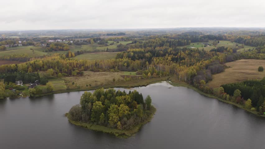 Drone of lonely island with a forest in the middle of a lake (autumn)