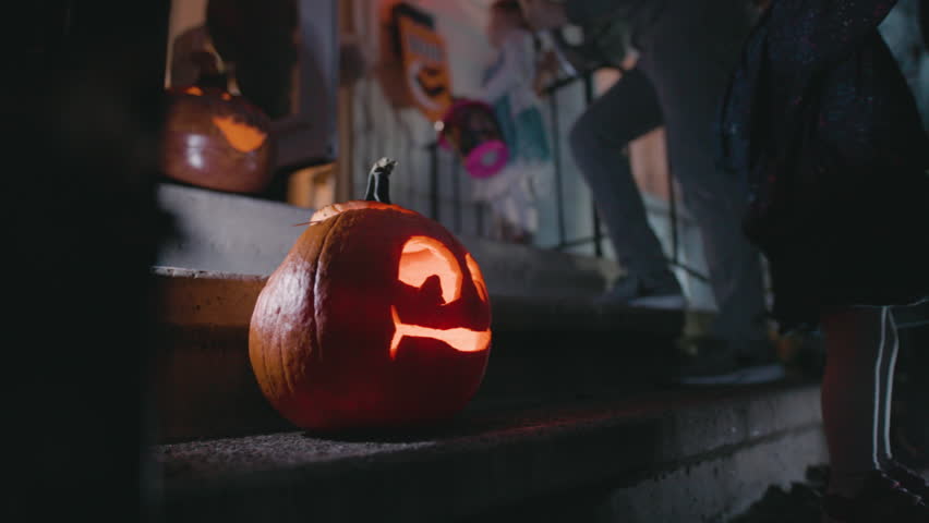 Kids trick or treating out of focus behind jack o lantern Royalty-Free Stock Footage #1099742763
