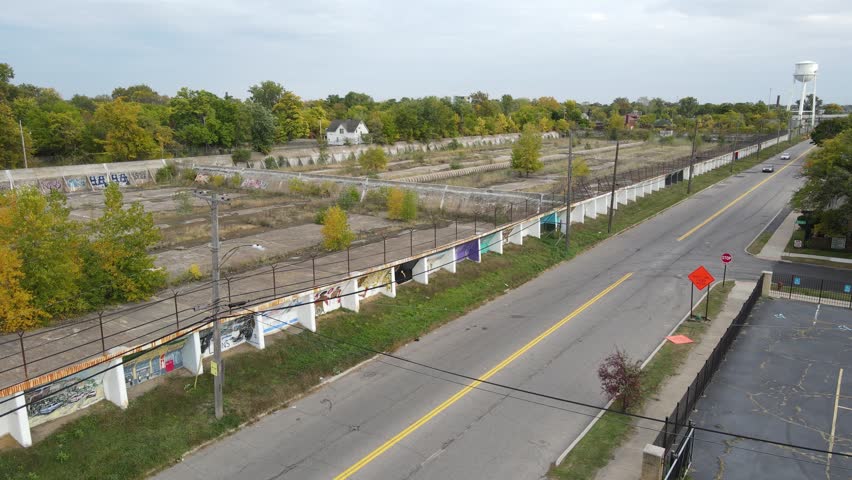 Cars driving pass abandoned concrete water reservoir in Detroit, aerial view