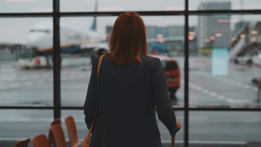 Woman with suitcase walking in airport terminal. | Shutterstock HD Video #1099755079