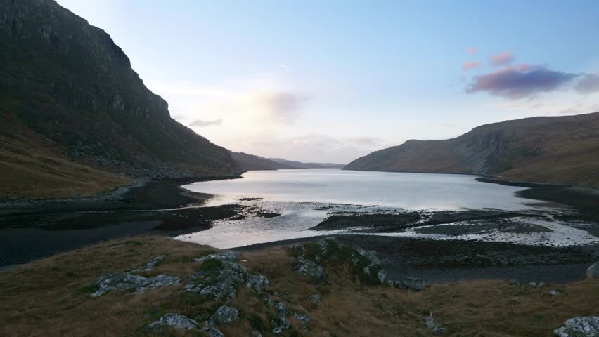 Water slowly flows into a sea loch (Gleann Dubh) at low tide in the highlands of Scotland at sunset.