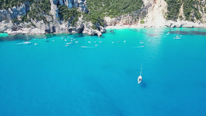 Tourist Boats Enjoy Summer Vacation at Cala Goloritze Beach Rock Formations in Sardinia, Italy - Aerial 4k Tilting Reveal