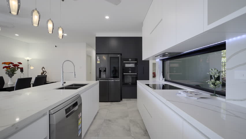 Modern Luxurious Contemporary kitchen white marble bench top drop lighting marble tiled floors black feature wall with sleek black appliances fridge white kitchen storage red appliances