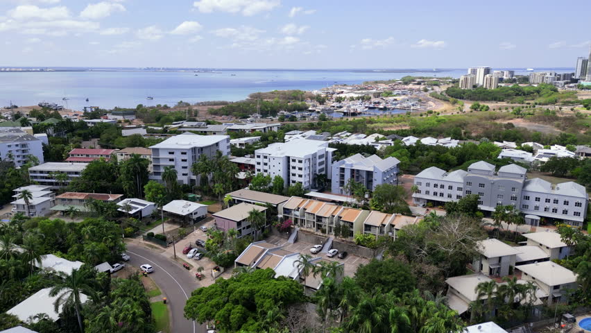 Aerial drone footage of marina blue ocean sea water. Boats and yachts. Tropical greenery palm tree. Luxurious houses properties homes. apartment complexes. Skyline of Darwin city.