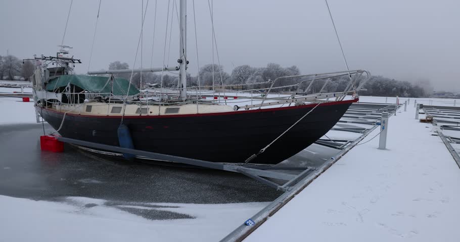 Aerial View of dead frozen harbour docks with boat and ice below. Extreme cold weather. Nature landscape famous for being heavily affected by global warming and Climate Change. Mooring for yachts