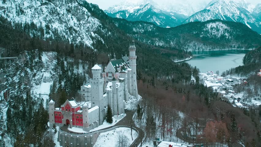 Aerial drone view Neuschwanstein castle on Alps background in vicinity of Munich, Bavaria, Germany, Europe. Winter landscape with castle and lake in snowy mountains covered with spruce forest.  Royalty-Free Stock Footage #1099762659