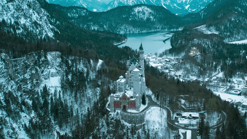 Aerial drone view Neuschwanstein castle on Alps background in vicinity of Munich, Bavaria, Germany, Europe. Winter landscape with castle and lake in snowy mountains covered with spruce forest.  Royalty-Free Stock Footage #1099762661