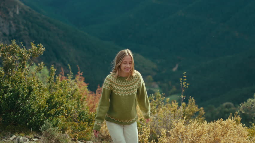 Cinematic woman in traditional sweater walk in mountain. Pure happiness from outdoor lifestyle and connect with nature. Sunny vacation and explore Europe.