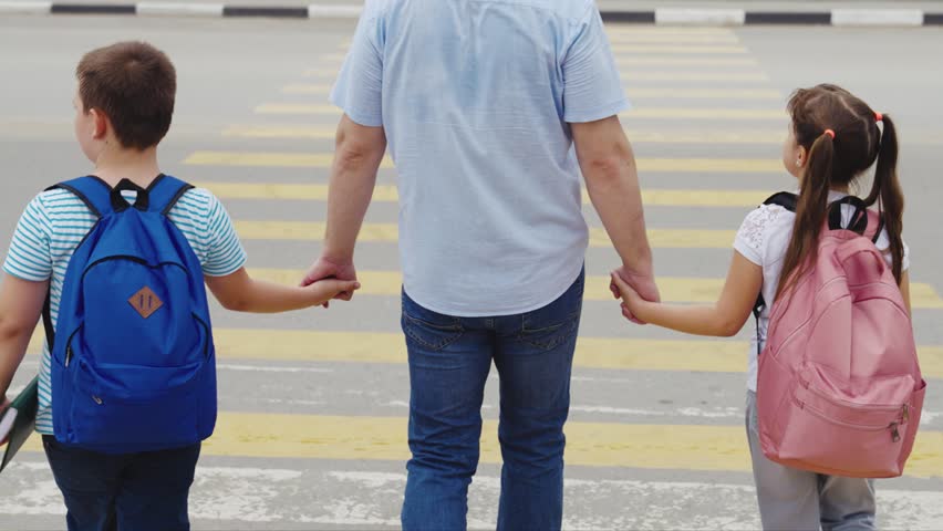 Father leads children to school through pedestrian crossing. happy family. zebra road. group child girl boy go to school with school backpacks. happy family concept. school students. parent with kid