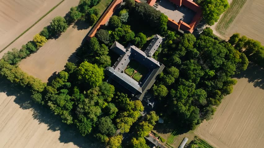 Drone shot of a symmetrical monastery in surrounded by green tree's in a country landscape | Shutterstock HD Video #1099772753