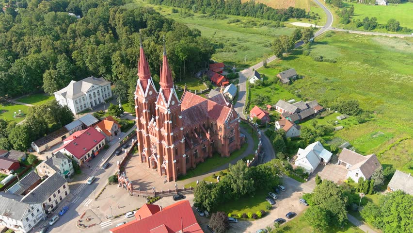 Majestic tall church in small township of Sveksna, Lithuania, aerial orbit view