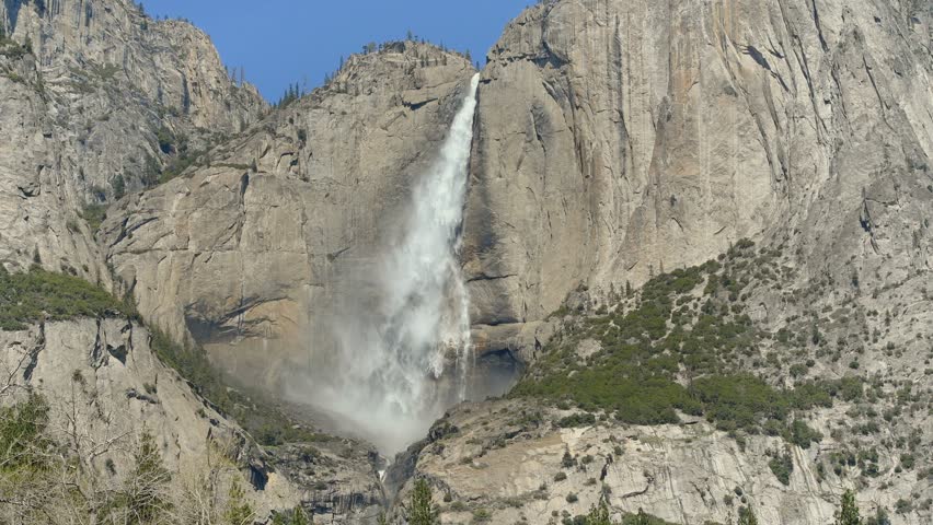 Spring Upper Yosemite Falls - Closeup view of spectacular Upper Yosemite Falls roaring off 1,430-feet (440 m) steep granite cliff wall on a sunny Spring morning. Yosemite National Park, California, US