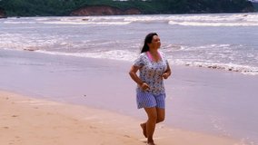 running along sea, mature charismatic plump woman 55 years in shorts runs barefoot along seashore, concept of outdoor aerobic training, active lifestyle, health running for health of elderly, video