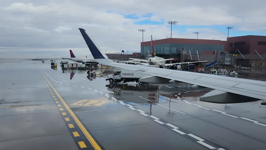 SALT LAKE CITY, UTAH - 29 DEC 2022: Salt Lake City Utah airport airline taxi to terminal 3. Vacation or business travel by commercial airliner. Winter storm snow and rain. Terminal.