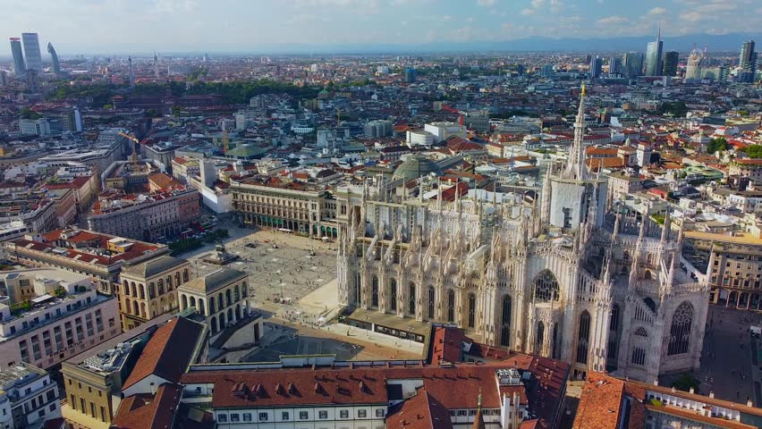 Aerial view of Piazza Duomo in front of the gothic cathedral in the center. Drone view of the gallery and rooftops during the day. Flight over the city. People in the city. Milan. Italy Royalty-Free Stock Footage #1099779437