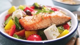 Greek salad and grilled salmon fish in bowl. Traditional mediterranean cuisine Choriatiki salad. Healthy food, diet. Stock video 4k