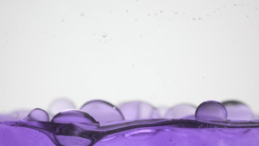 Background shot for cosmetics with bakuchiol commercial | Macro shot of a lot of different sized purple clear bubbles fall down to purple surface bouncing and bursting on grey background Royalty-Free Stock Footage #1099794583