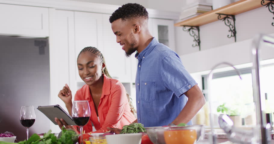 Happy african american couple preparing meal in kitchen. Lifestyle, relationship, spending free time together concept. | Shutterstock HD Video #1099803797
