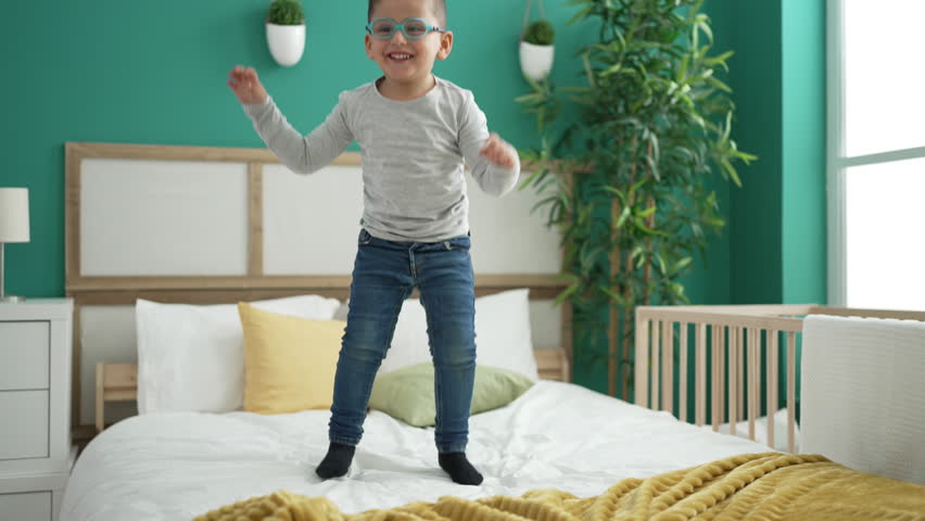 Adorable hispanic toddler smiling confident jumping on bed at bedroom | Shutterstock HD Video #1099803895