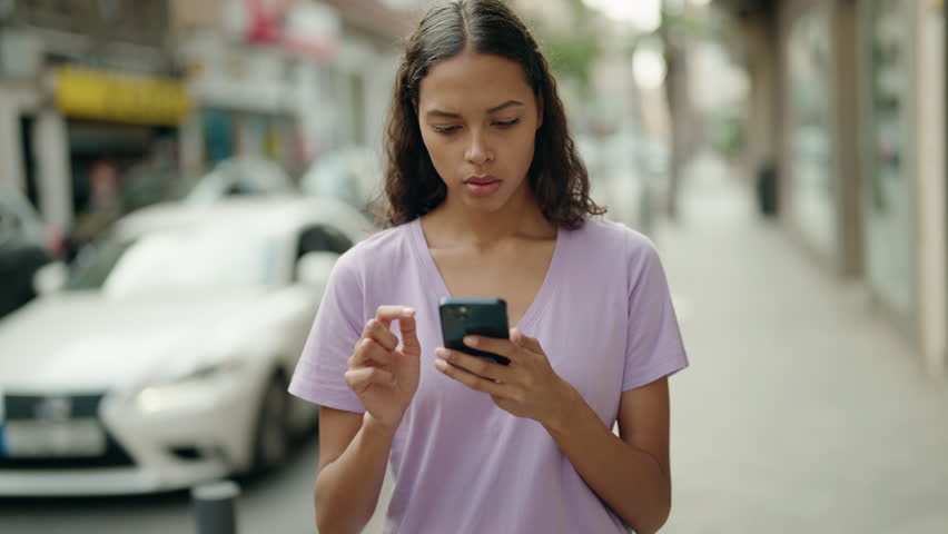 Young african american woman using smartphone with worried expression at street | Shutterstock HD Video #1099804503