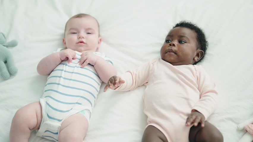 Two adorable babies smiling confident lying on bed at bedroom