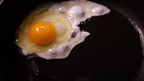 Eggs are fried in a pan. A raw egg falls. Cooking scrambled eggs slow motion video.