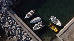 Video of boats, fishing boats moored in a small port. Calm and crystalline sea, beach and rocks.