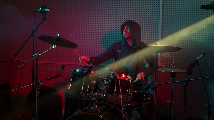 Drummer performs at percussion instruments at rock concert. Tympanist man plays drums, musical cymbals at show. Musician in hoody at rehearsal, participates in recording of album in sound studio | Shutterstock HD Video #1099806435