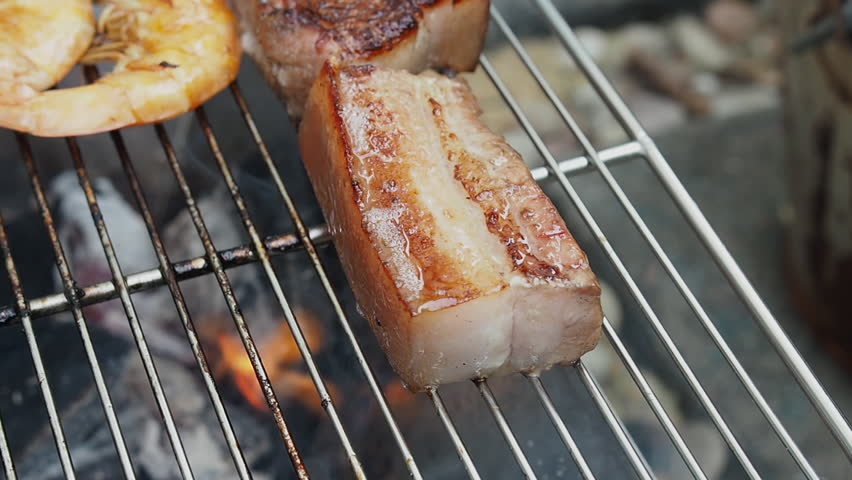 Streaky pork on hot iron grill. Chef uses tongs to turn pork steaks on grill grate.Barbecue Asian style. Royalty-Free Stock Footage #1099814789