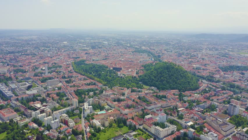 Inscription on video. Graz, Austria. The historic city center aerial view. Mount Schlossberg (Castle Hill). Different colors letters appears behind small squares, Aerial View