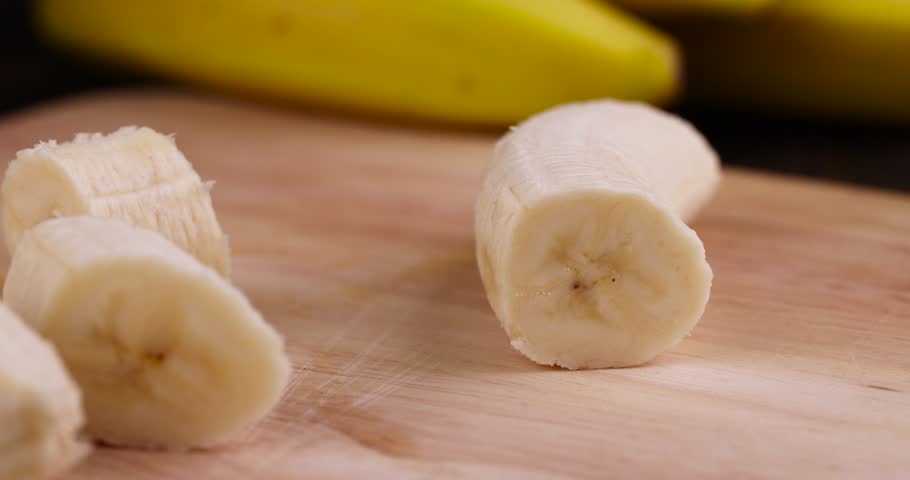 A ripe sweet banana cut into pieces lies on the table , ripe yellow bananas on a wooden board | Shutterstock HD Video #1099817393