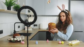 Young woman food blogger records video on digital cam while baking Easter cake. Happy easter. Female telling how to preparing for holidays. Online Learning