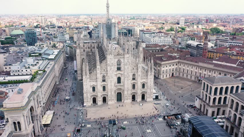 The drone rotates around The Milan Cathedral with a lot of people walking on the square on a summy day in Milan Italy Aerial Drone Footage 4k