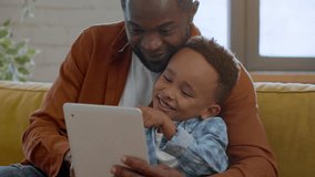 Modern kids development. Close up portrait of cute little african american boy playing education game on digital tablet with his loving daddy, tracking shot, slow motion - Powered by Shutterstock - Get 15% off with code: PIKWIZARD15